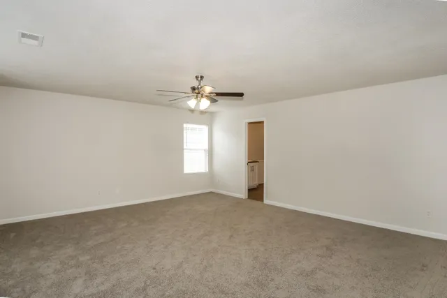 a view of an empty room with a chandelier fan
