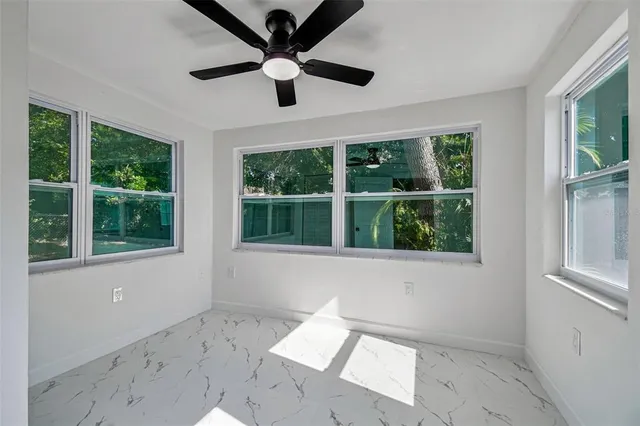 a view of an empty room with a window and a ceiling fan