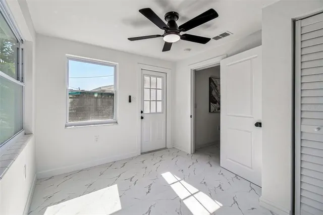 a view of a big room with a chandelier fan and windows