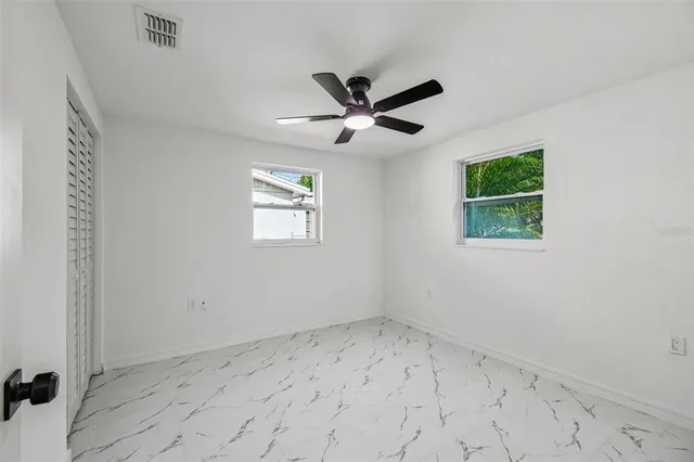 an empty room with a window and a fan