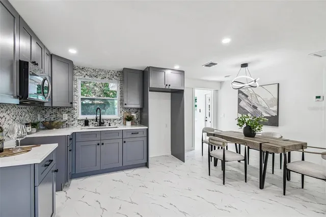 a kitchen with stainless steel appliances granite countertop a table chairs sink refrigerator and cabinets