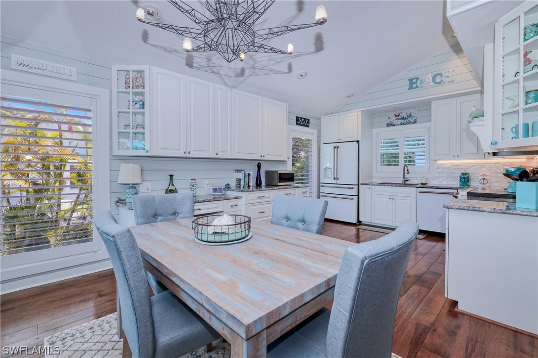 1021 Sand Castle Road Sanibel, FL 33957 - Photo 20 of 49 a kitchen with stainless steel appliances granite countertop a stove a refrigerator a microwave oven a dining table and chairs with wooden floor