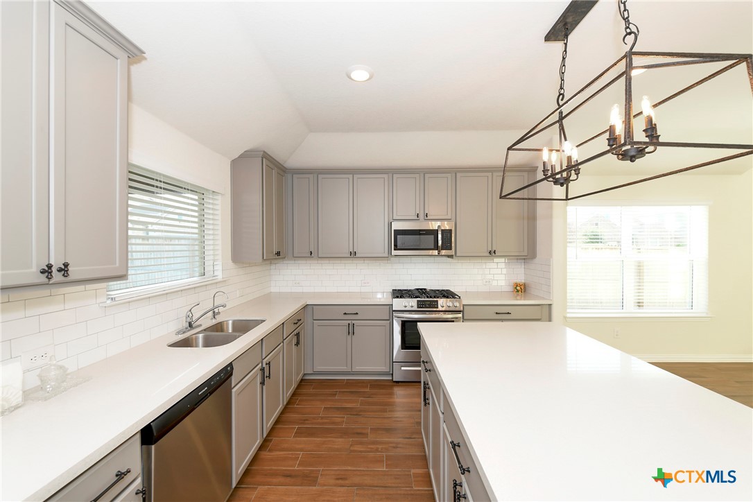 2069 Flametree Avenue New Braunfels, TX 78132 - Photo 18 of 46 a kitchen with stainless steel appliances a sink a stove a refrigerator cabinets and a window