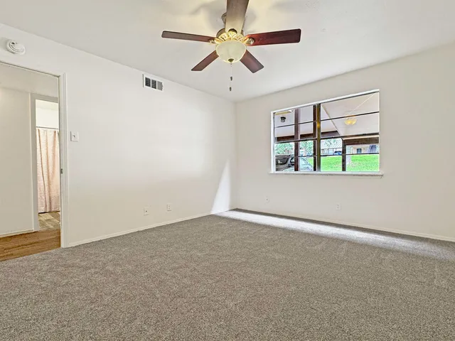 an empty room with windows and ceiling fan