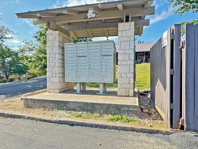a view of a brick house with a small yard and large tree
