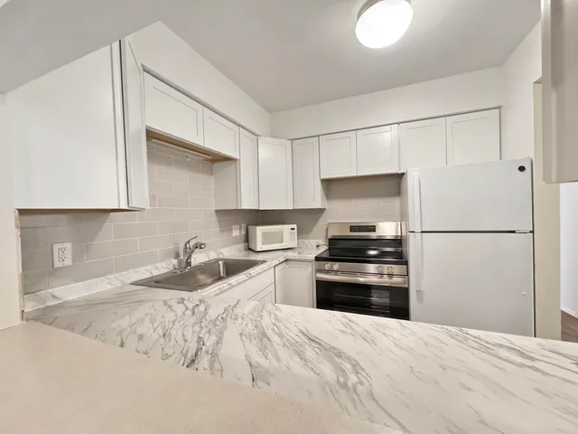 a kitchen with granite countertop a refrigerator stove and sink