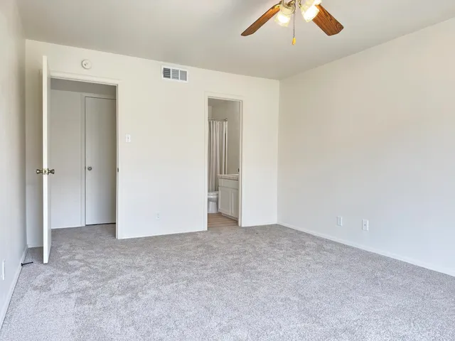 an empty room with closet and chandelier fan