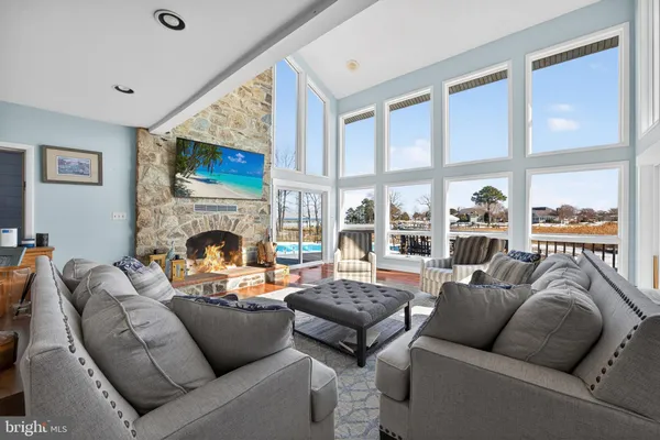 a view of a livingroom with furniture a fireplace wooden floor and windows