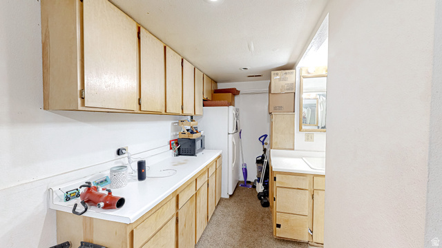 630 1100 West Provo, UT 84601 - Photo 34 of 64 Functional utility space featuring extensive light wood cabinetry, white laminate countertops, and a built-in sink area