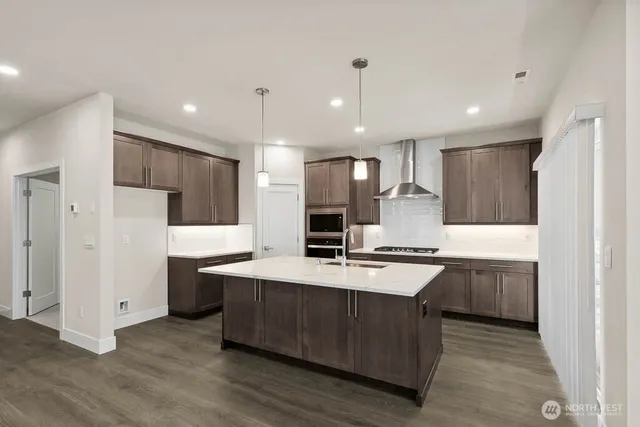 a large kitchen with stainless steel appliances kitchen island granite countertop a stove and a refrigerator