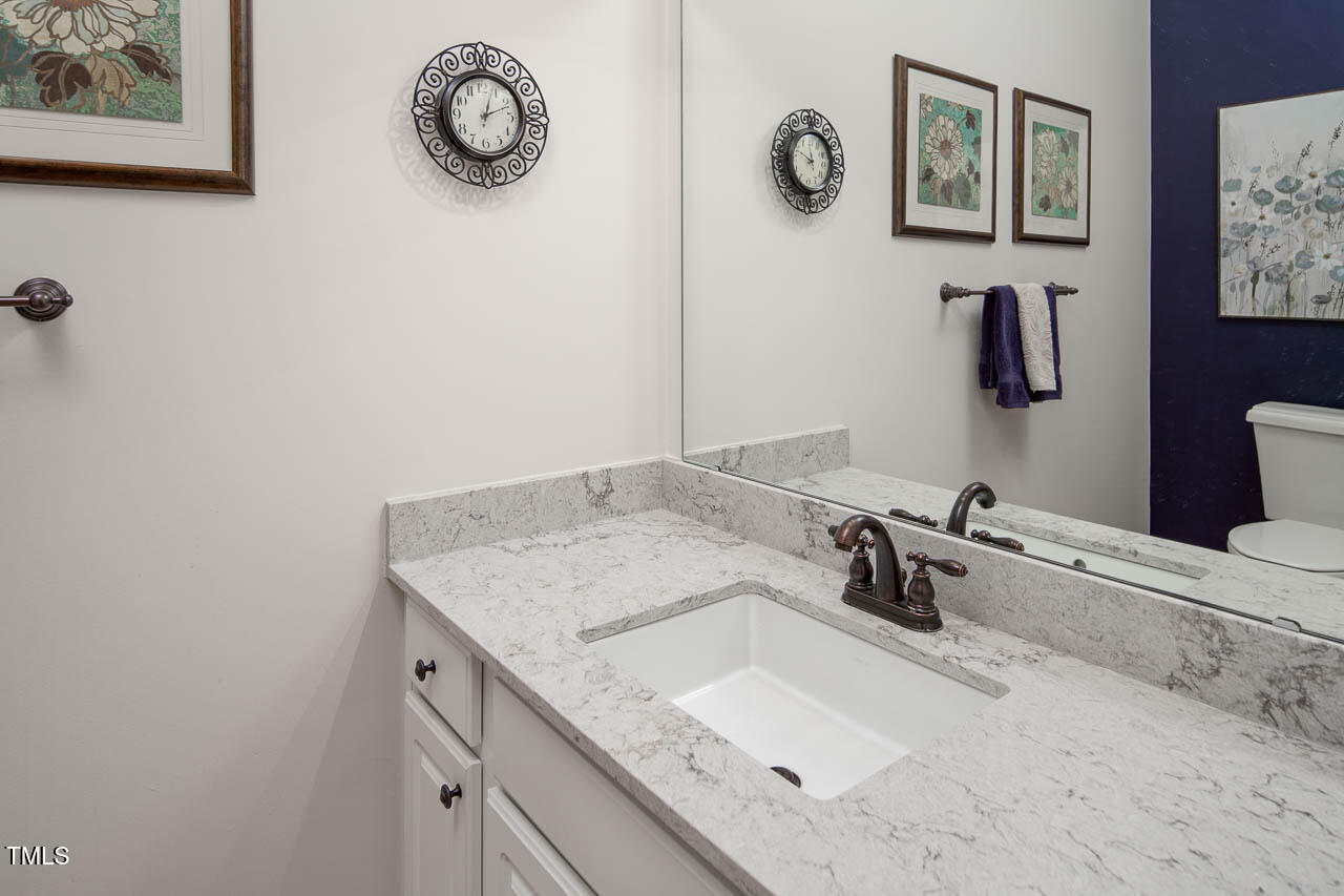 1059 Torrence Drive Apex, NC 27502 - Photo 32 of 49 a bathroom with a granite countertop sink and a mirror