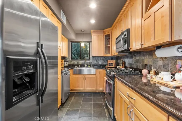 a kitchen with stainless steel appliances granite countertop a refrigerator a sink and white cabinets