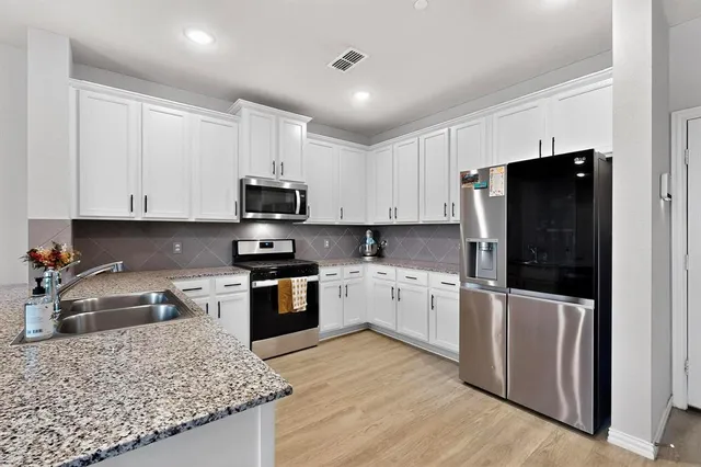 a kitchen with granite countertop white cabinets and stainless steel appliances