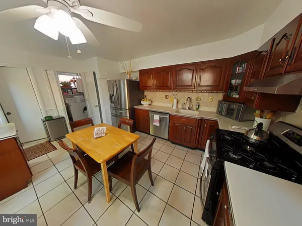 a kitchen with stainless steel appliances a stove a refrigerator a sink a dining table and chairs with wooden floor