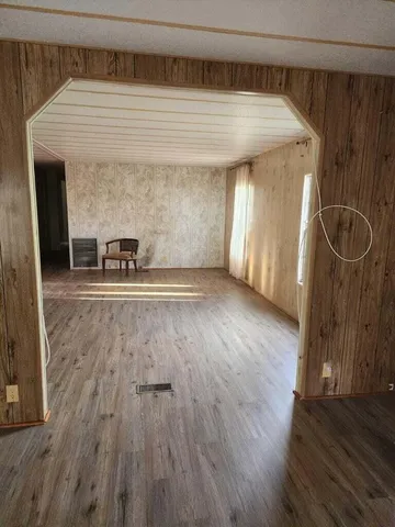 a view of an empty room with a fireplace and wooden floor