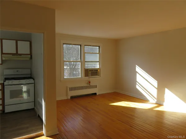 an empty room with wooden floor cabinet and windows