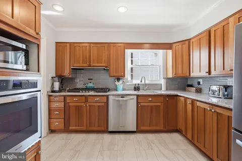 a kitchen with stainless steel appliances granite countertop wooden cabinets a sink and dishwasher with wooden floor