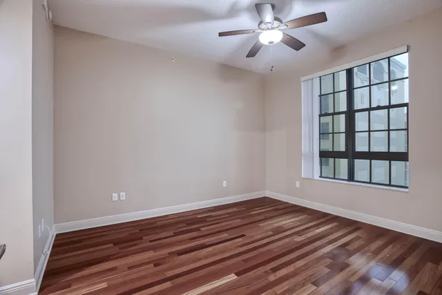 a view of an empty room with a chandelier fan and kitchen view