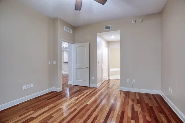 a view of empty room with wooden floor and fan