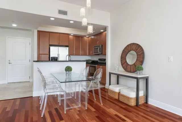 a kitchen with stainless steel appliances granite countertop a stove top oven a sink a dining table and chairs with wooden floor