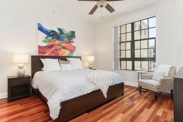 a bedroom with a bed a dresser and a large window