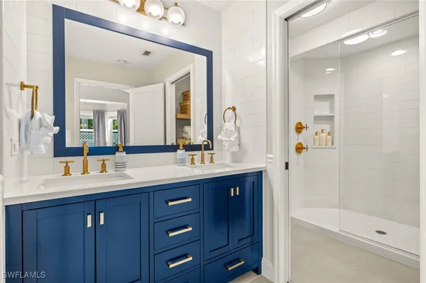 a bathroom with a double vanity sink and mirror with shower