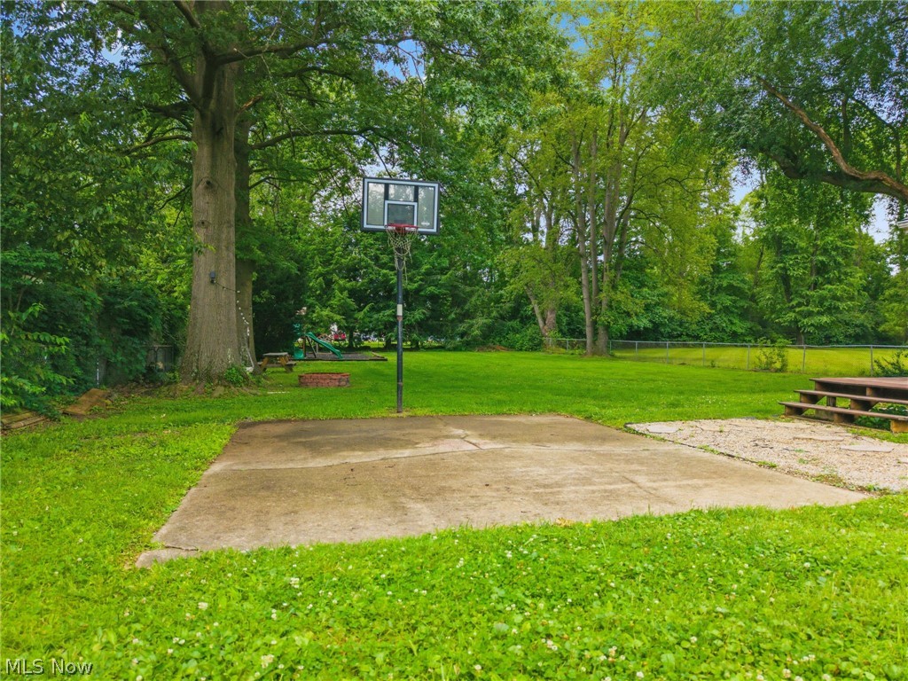 4449 18th Street Northwest Canton, OH 44708 - Photo 24 of 25 Expansive backyard featuring a concrete pad with a basketball hoop, a large grassy area, mature trees, and a multi-level wood deck