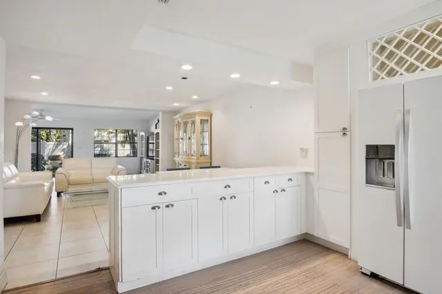 a large white kitchen with granite countertop a lot of white cabinets and wooden floor