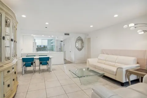 a living room with furniture a clock and a view of kitchen