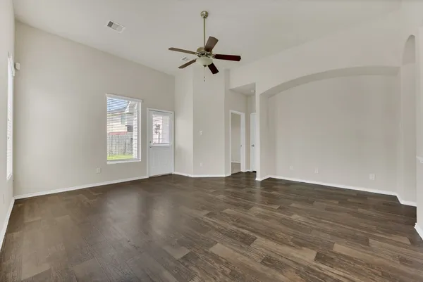 a view of an empty room with wooden floor and a window