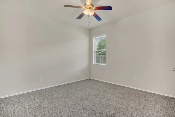 an empty room with a window and a fan