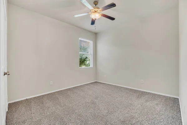 an empty room with a window and a fan