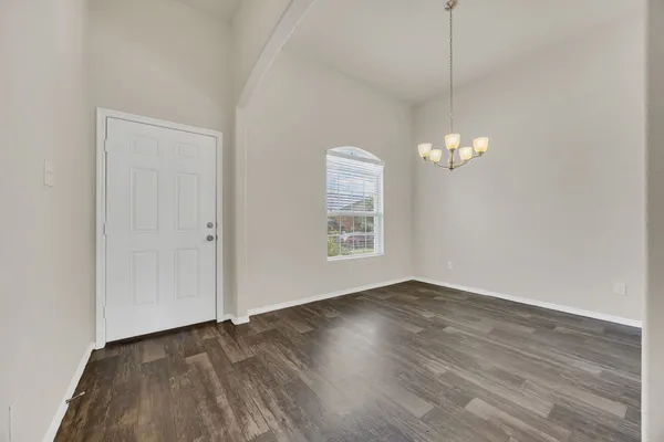 an empty room with wooden floor chandelier fan and windows