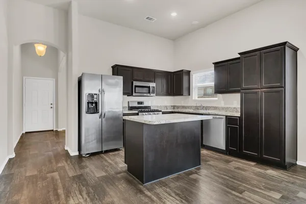 a kitchen with stainless steel appliances granite countertop a refrigerator and a stove top oven