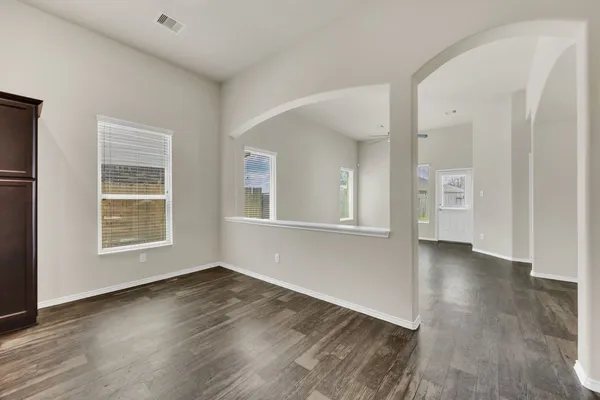 an empty room with wooden floor and windows