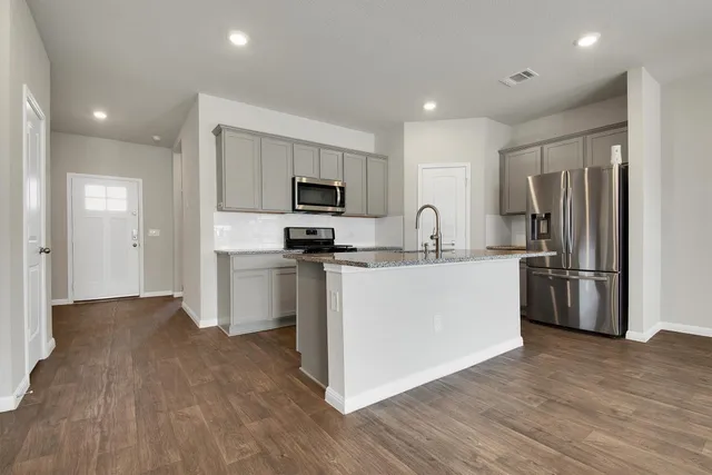 a kitchen with a refrigerator a stove top oven and wooden floor