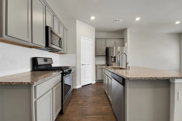 a kitchen with stainless steel appliances granite countertop a stove a sink and a refrigerator