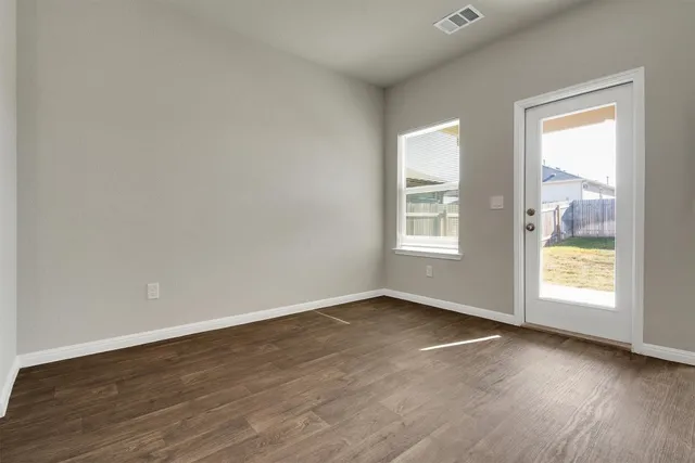 an empty room with wooden floor and windows