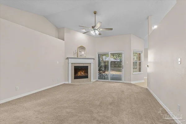 a view of a livingroom with a fireplace a ceiling fan and front door