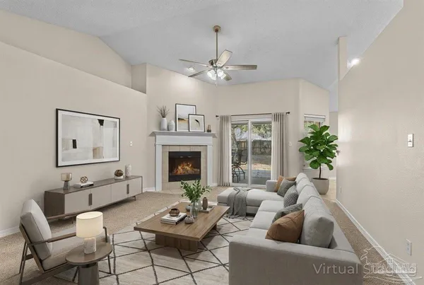 a view of an empty room with chandelier fan and fire place