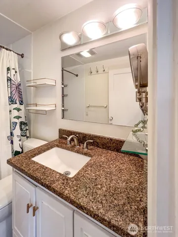a bathroom with a granite countertop sink and a mirror