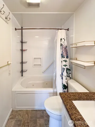 a bathroom with a granite countertop bathtub and a shower