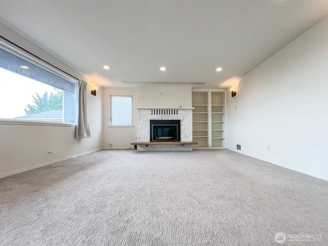 an empty room with windows and fireplace