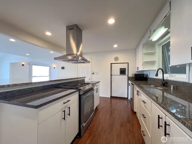 a kitchen with granite countertop a sink stove and refrigerator