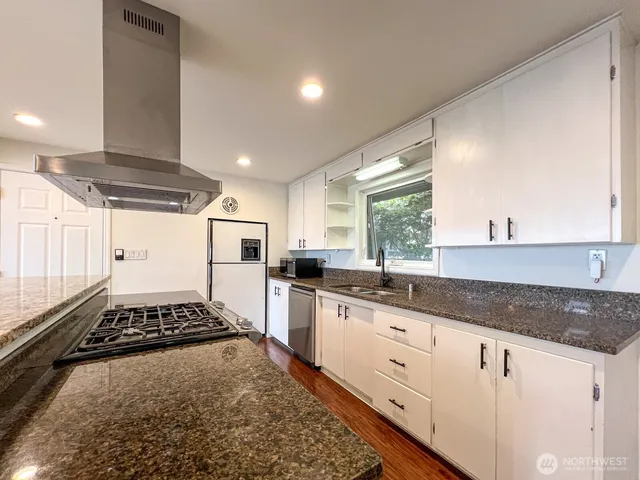 a kitchen with granite countertop stainless steel appliances a stove sink and cabinets