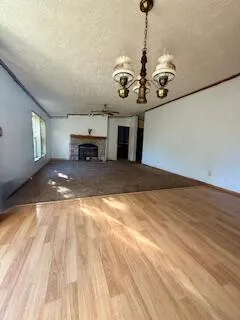 a view of a livingroom with a fireplace a chandelier and wooden floor