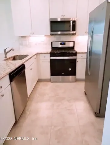 a kitchen with stainless steel appliances a sink a stove a microwave and wood floor