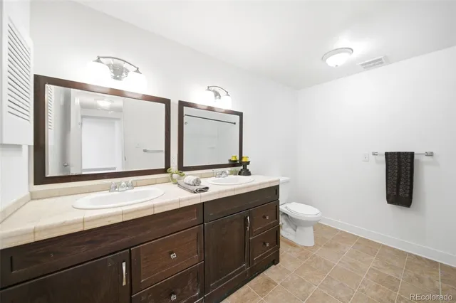 a bathroom with a granite countertop sink a toilet and shower