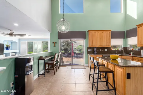 a kitchen with stainless steel appliances granite countertop a table chairs sink and wooden cabinets