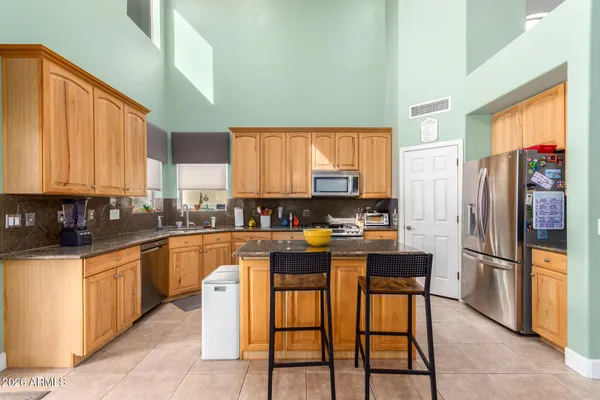 a kitchen with stainless steel appliances granite countertop a stove a refrigerator a sink a stove with island chairs and cabinets